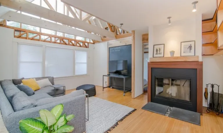 modern living room with vaulted ceilings, large windows, a sectional sofa, a fireplace, and a TV setup